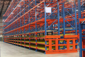 A side view of a row of SelecDeck Case Flow Rack with reserve Sentinel Selective Pallet Rack overhead.