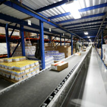 Conveyor moves products in a Pick Module pallet rack system.