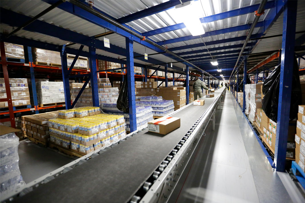 Conveyor moves products in a Pick Module pallet rack system.