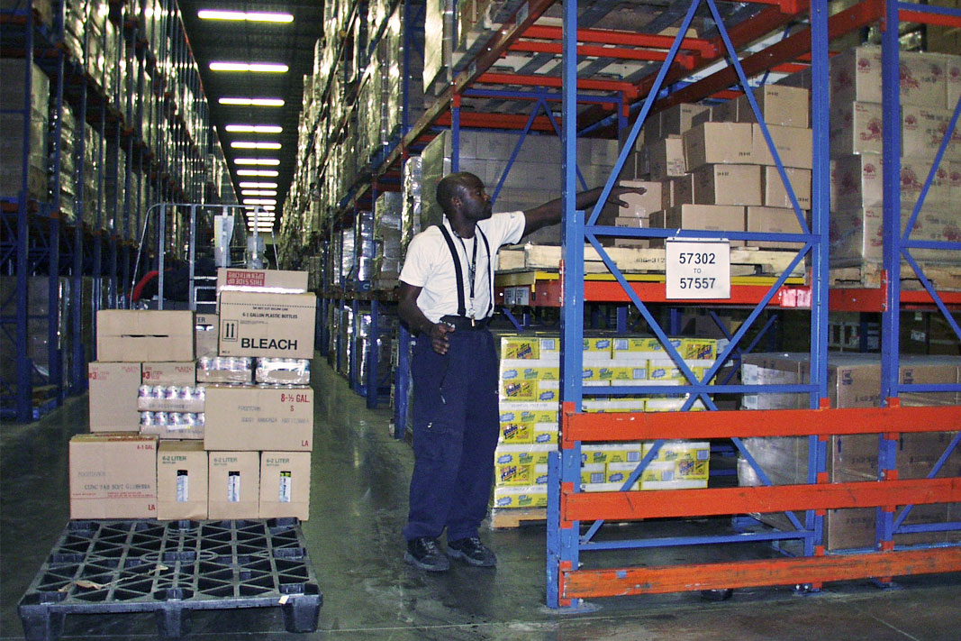 A worker picks product from Frazier's Glide 'N Pick® pallet rack cart.