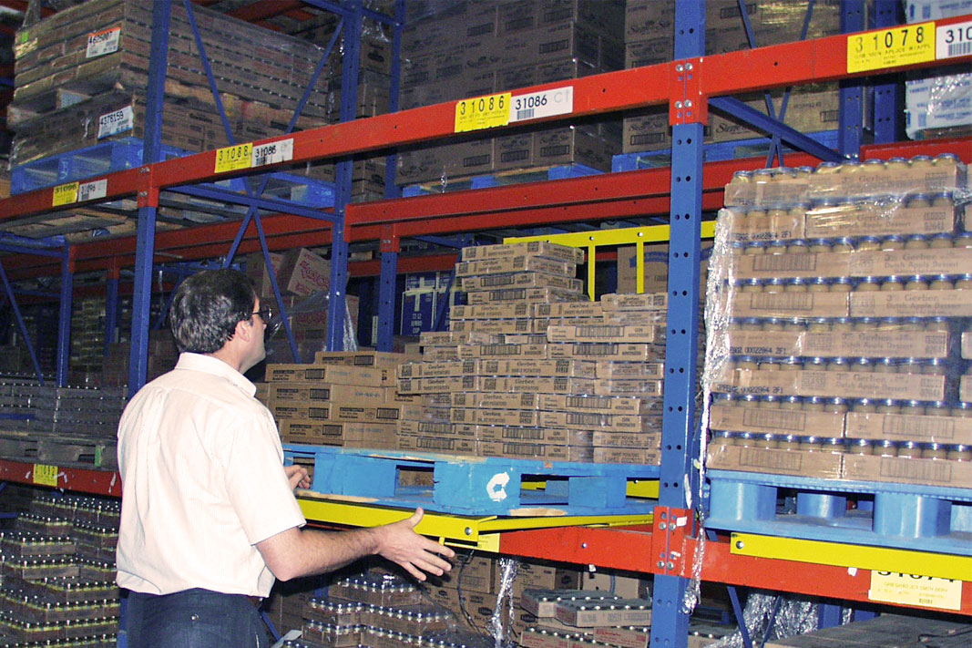 A worker picks product from Frazier's Glide 'N Pick® pallet rack cart.